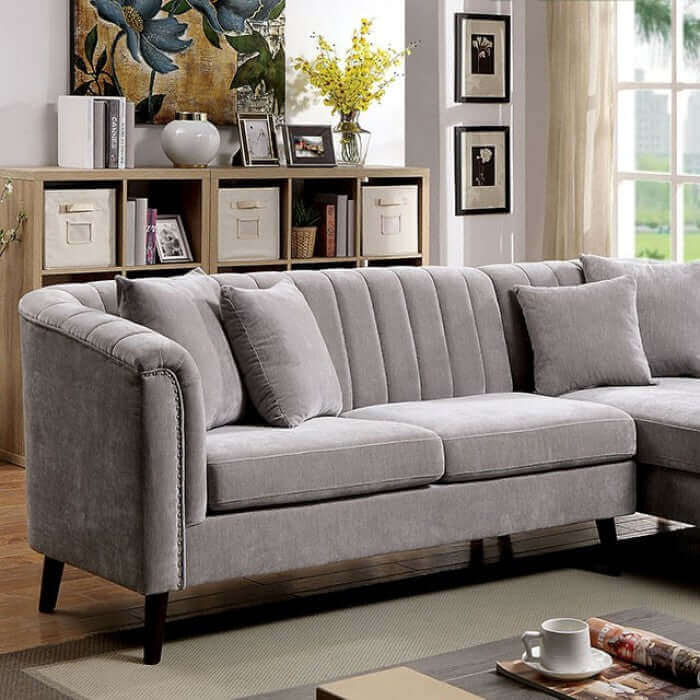 Goodwick Gray Sectional Sofa with button tufted back and plush cushions in stylish living room setting.