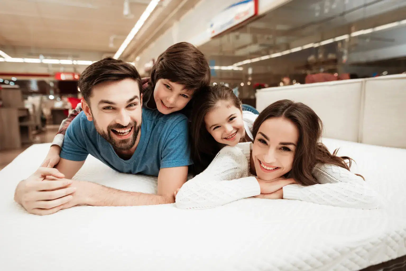 Family enjoying quality time on a mattress in a store, smiling together and creating lasting memories.