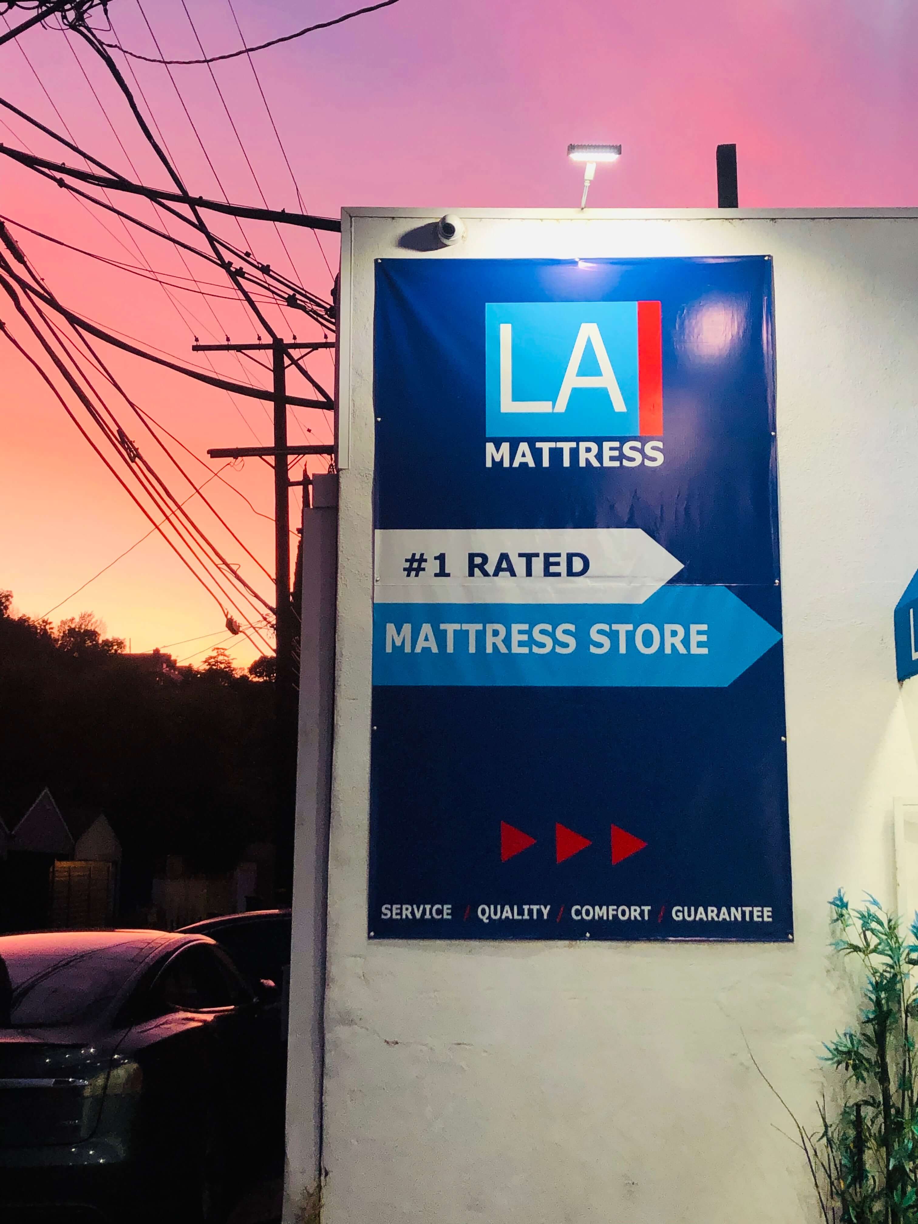 LA Mattress store sign showcasing "#1 Rated" with sunset background, emphasizing service, quality, and comfort.