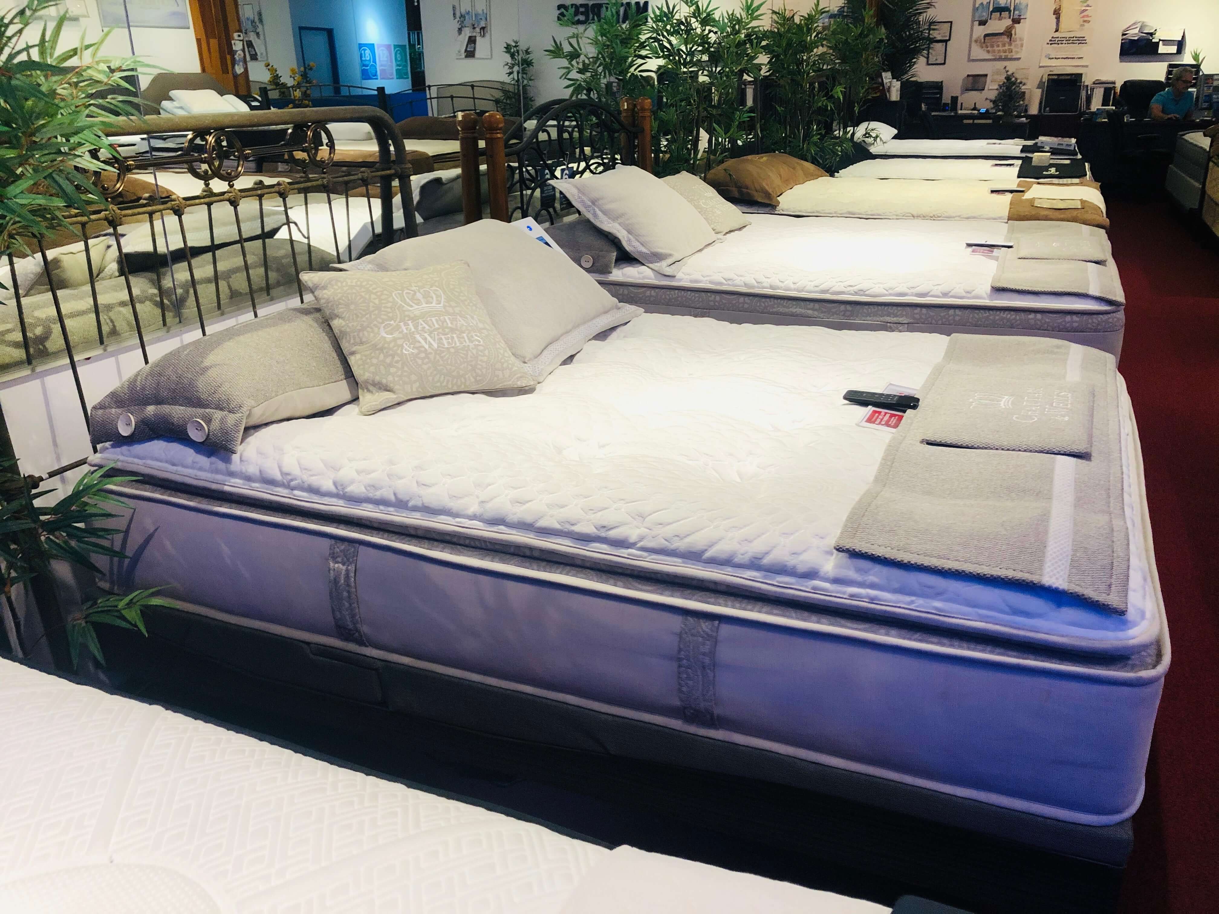 Display of comfortable mattresses with pillows in a furniture store showroom, showcasing bedding options for customers.