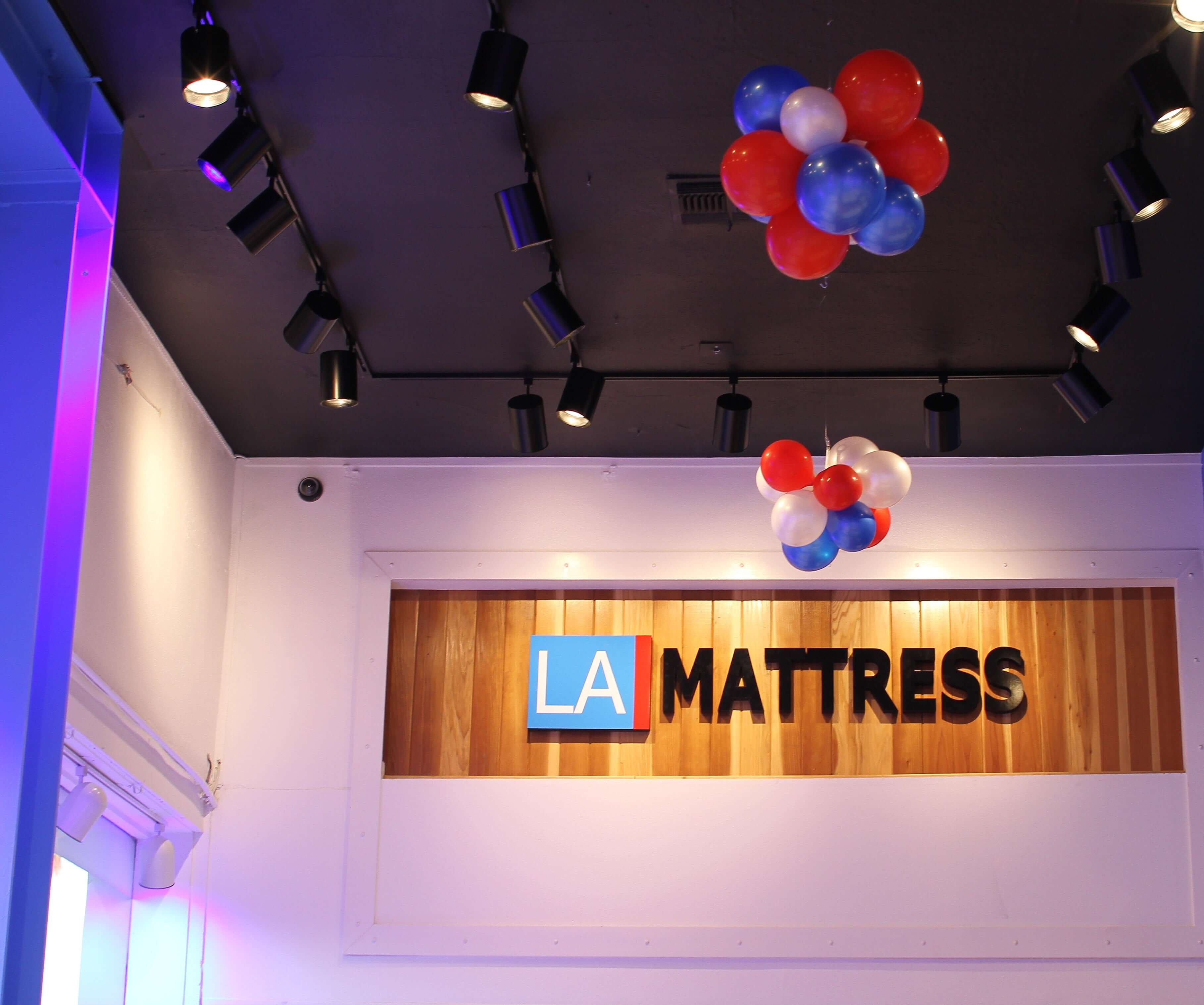 Interior view of LA Mattress store showcasing colorful balloons and modern lighting design.