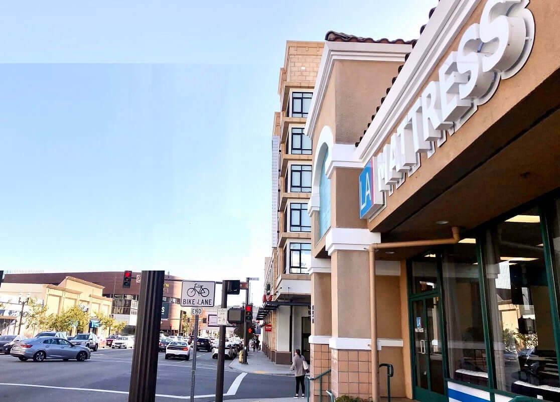 Street view of a fitness center and nearby traffic signals at a bustling intersection.