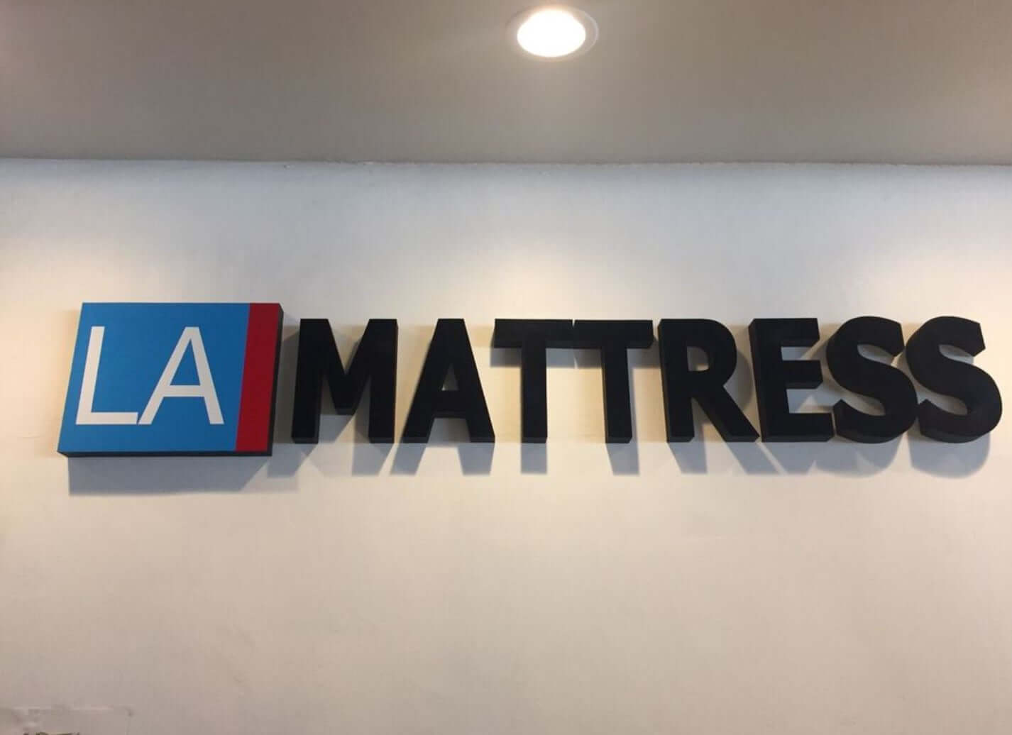 Signage of LA Mattress showcasing logo in bold letters against a light background.
