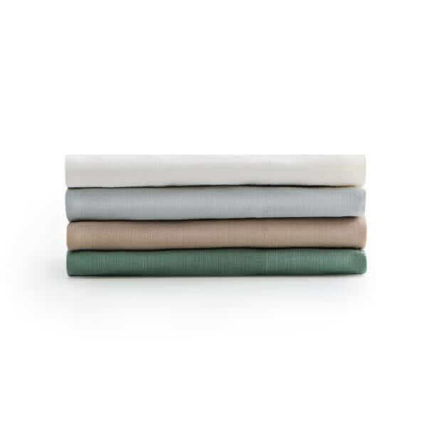 Stack of Malouf Fog Linen Weave Cotton sheets in white, gray, beige, and green colors for a stylish bedding option.
