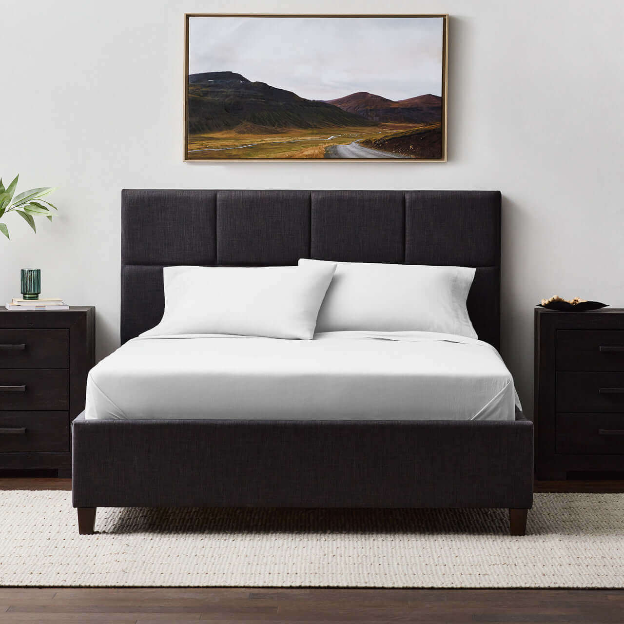 Modern bed with black upholstered headboard and Malouf Fog Linen Weave Cotton Sheet Set, framed landscape art on the wall.