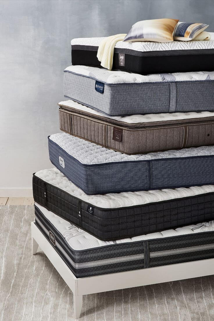 Stacked mattresses in various styles and colors on a white platform, showcasing comfort and design for bedroom decor.