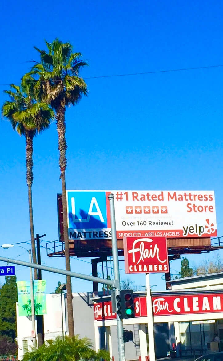 LA Mattress billboard featuring reviews and palm trees in sunny Los Angeles. #1 rated store with over 160 reviews.