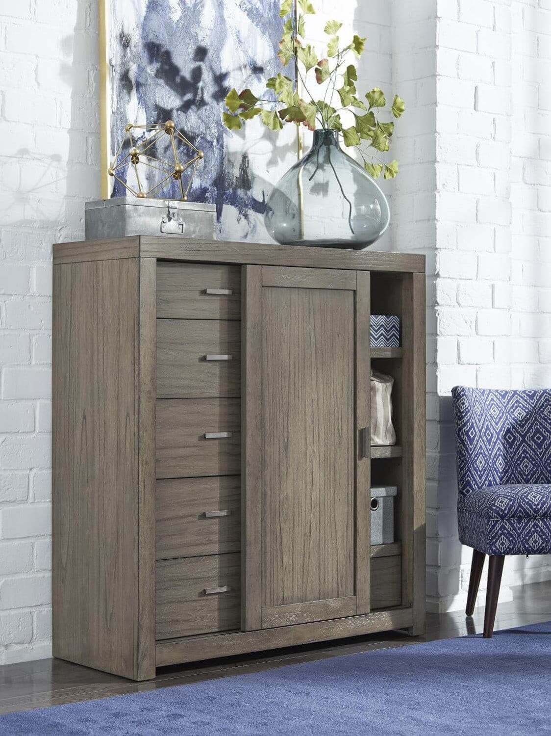 Modern Loft Collection Graystone Sliding Door Chest with aged bronze hardware against a white brick wall.