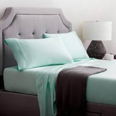 Malouf Opal Botanical Tencel™ Lyocell Sheet Set in mint green on a cozy bed with grey headboard and stylish lamp.