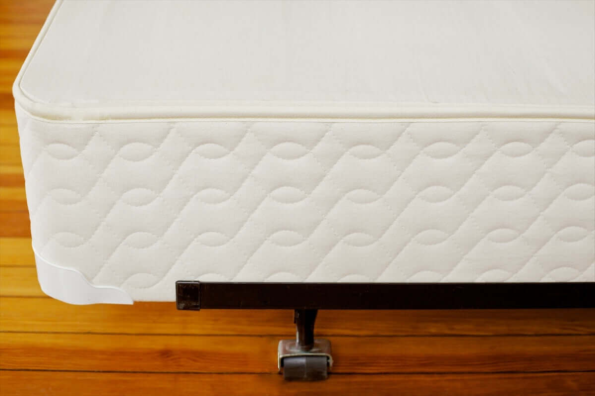 Savvy Rest Standard Profile 9" Mattress Foundation on a wooden floor, showcasing its natural fabric and sturdy design.