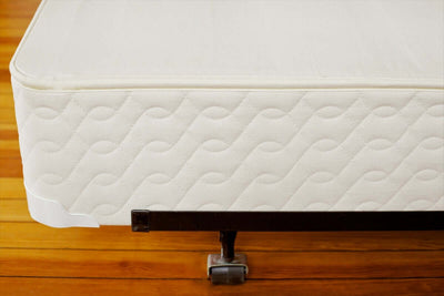 Savvy Rest Standard Profile 9" Mattress Foundation on a wooden floor, showcasing its natural fabric and sturdy design.
