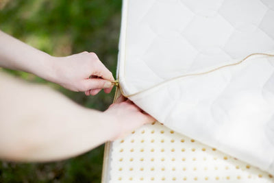 Person zipping organic latex mattress cover, showcasing GOTS-certified materials for comfort and sustainability.