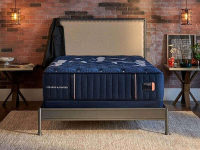 Stearns & Foster Lux Estate Ultra Firm 14.5" mattress displayed in a stylish bedroom setting with brick wall backdrop.