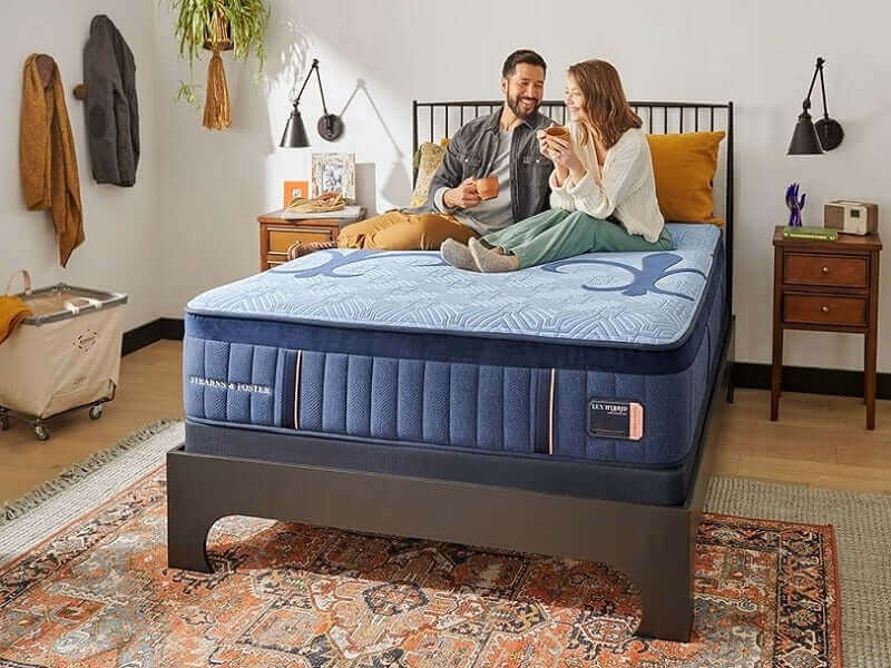 Couple enjoying comfort on Stearns & Foster Lux Hybrid Medium 14" Mattress in a cozy bedroom setting.