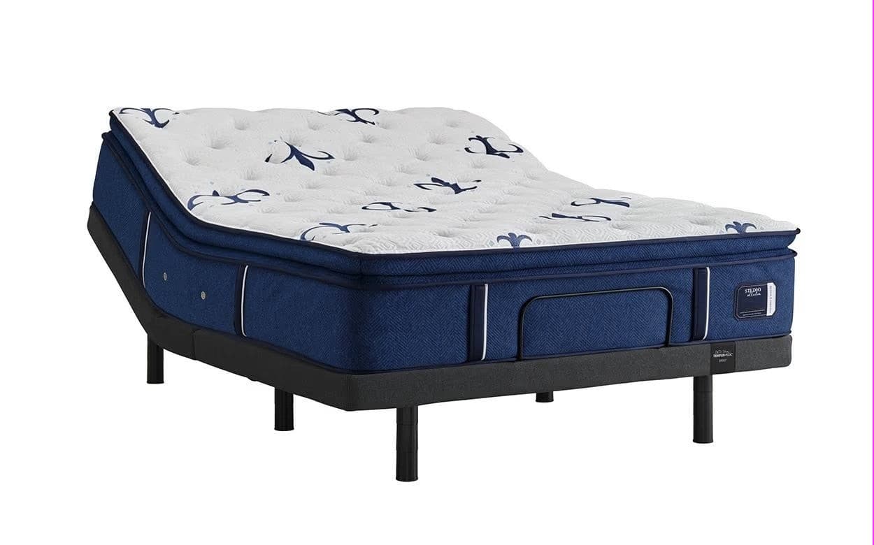 Stearns & Foster Studio Medium Euro Pillow Top 14.5" mattress with blue upholstered base and elegant floral design on top.