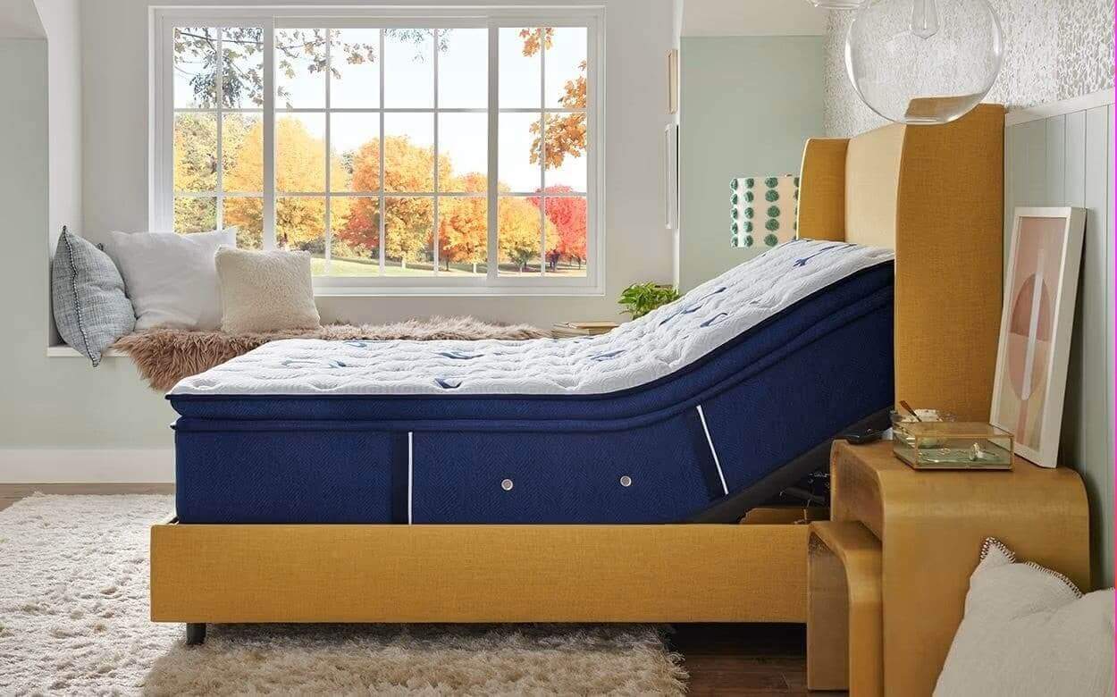 Stearns & Foster Studio Medium Euro Pillow Top mattress positioned in a modern bedroom with large window and autumn view.