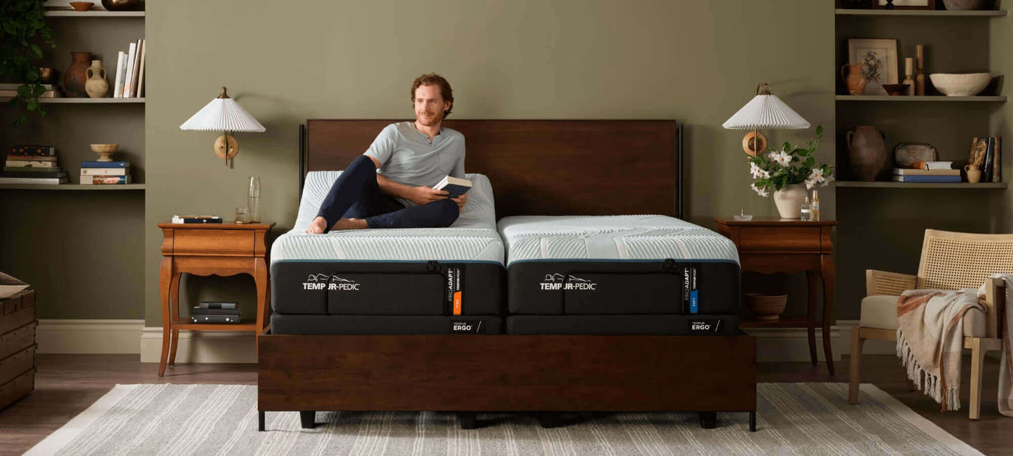 Man sitting on a twin TEMPUR-ProAdapt® Soft 12" Mattress in a stylish bedroom, showcasing comfort and design.