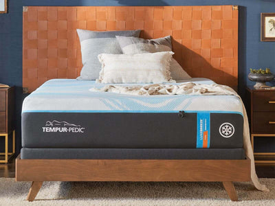 Tempur-Pedic TEMPUR-LuxeBreeze Firm mattress on a wooden bed frame with decorative pillows and a cozy blanket.