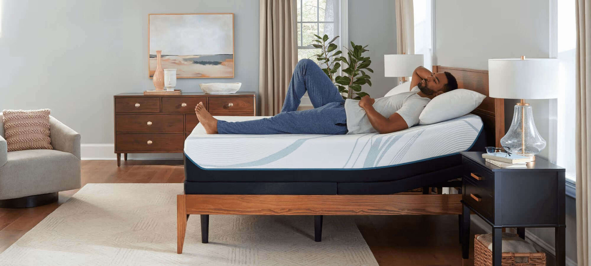 Man relaxing on Tempur-Pedic TEMPUR-Adapt 11" Medium Mattress in a modern bedroom setting.