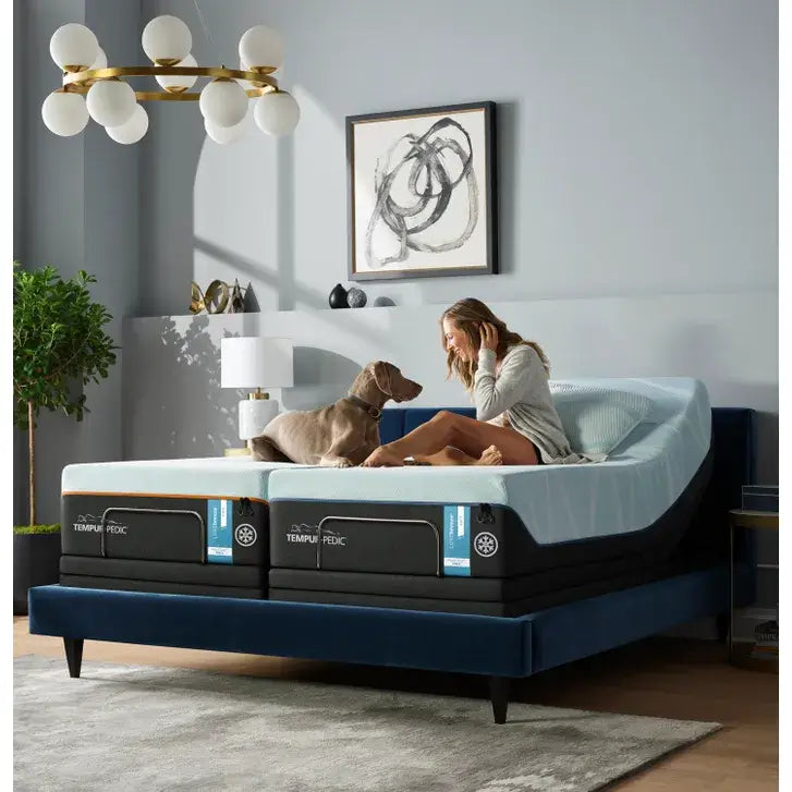 Woman relaxing on a Tempur-Pedic mattress with a dog in a stylish bedroom setting, showcasing comfort and design.