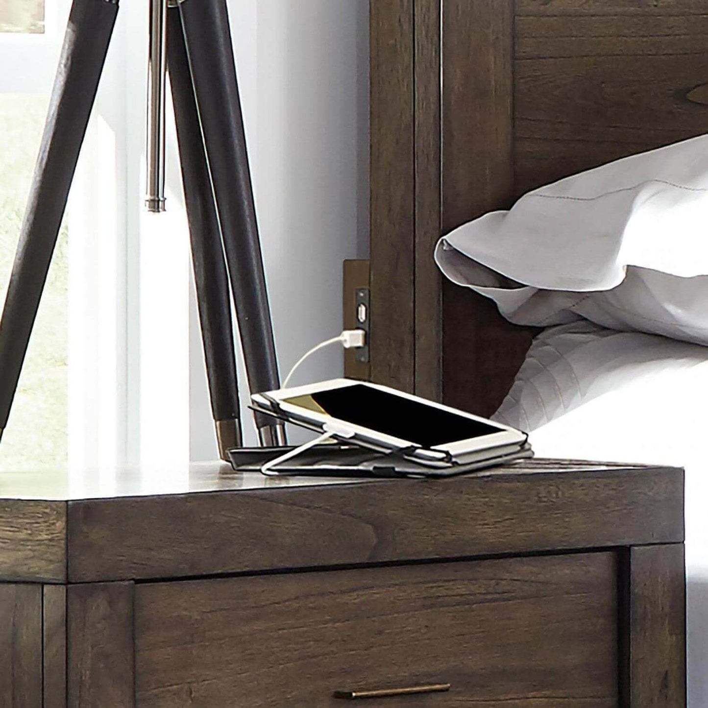 Modern loft nightstand with charging smartphone and stylish lamp, showcasing a cozy bedroom setting.