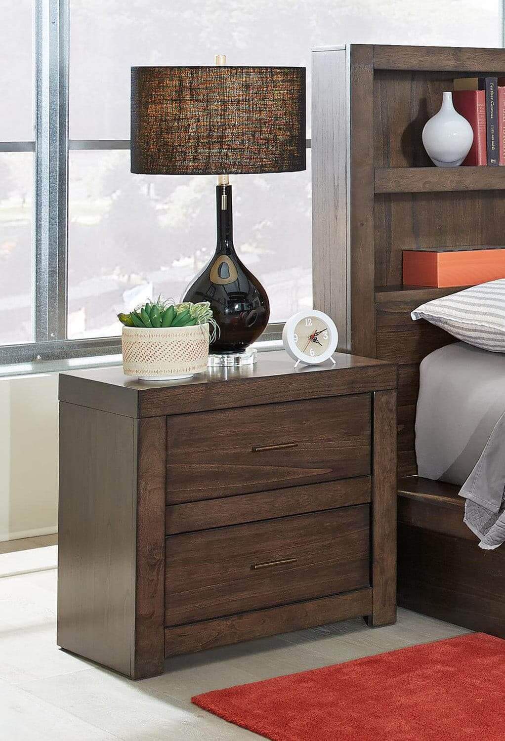 Modern Loft Brownstone nightstand with aged bronze hardware and lamp in a stylish bedroom setting.