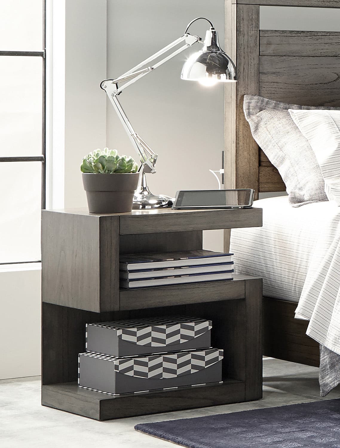 Modern Loft Collection Graystone Nightstand with lamp, plant, and decorative boxes, showcasing stylish design and functionality.