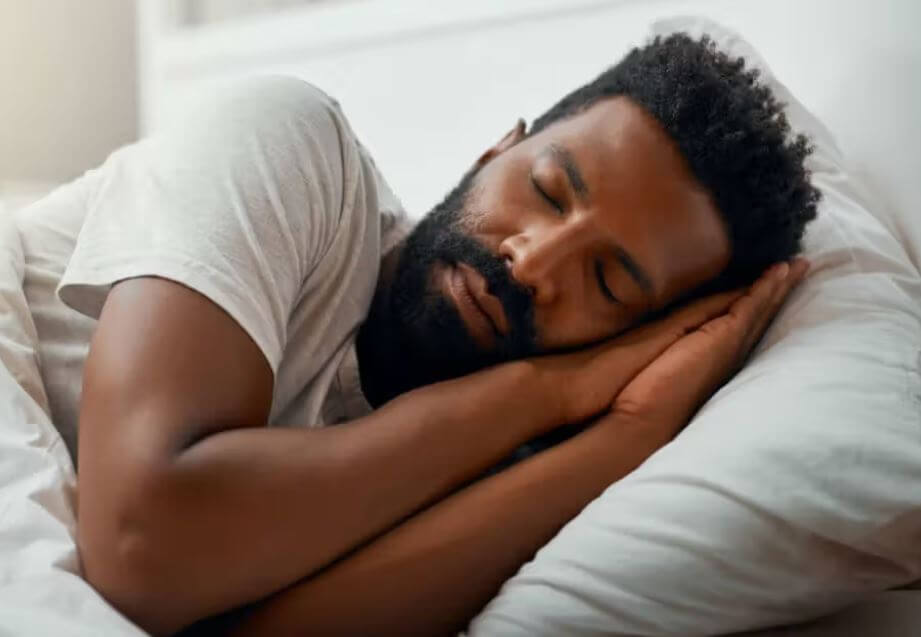 A man peacefully sleeping on a pillow, showcasing restful sleep and relaxation in a cozy bedroom setting.
