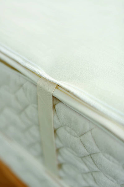 Close-up of King Savvy Rest organic wool mattress pad with organic cotton corner ties for secure fit on a mattress.