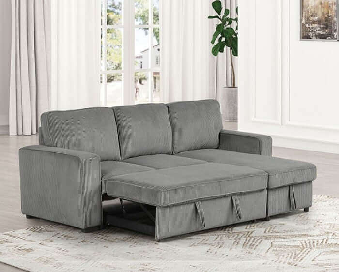 Contemporary dark gray Yves Corduroy sectional sofa with pull-out sleeper and reversible chaise on a stylish rug.