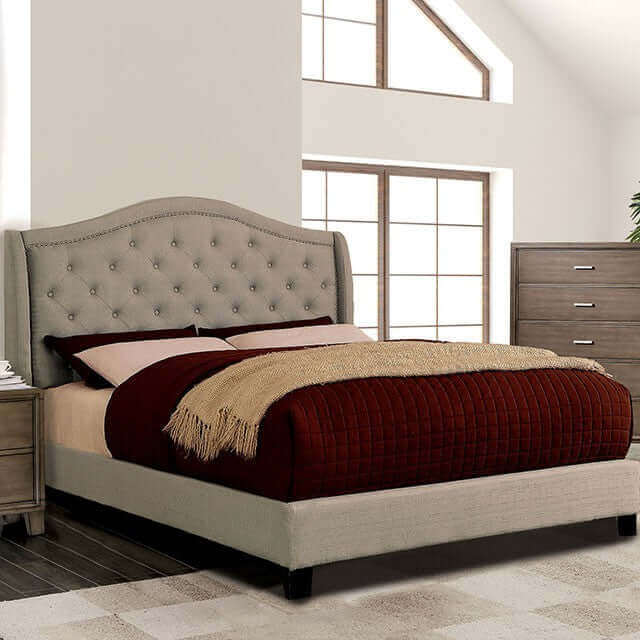 Carly tufted platform bed in gray linen with button headboard, styled with warm bedding in modern bedroom setting.