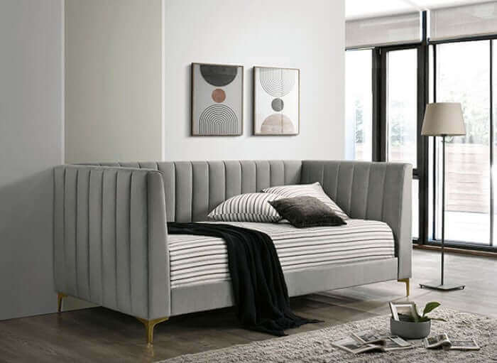 Elegant light gray daybed with tuxedo design, gold legs, and soft flannelette upholstery in a modern living room setting.