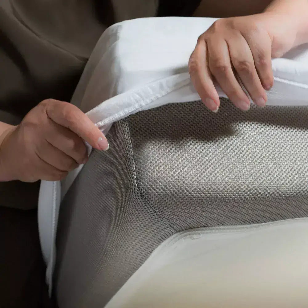 Hands adjusting a Cool Tencel Waterproof Mattress Protector on a mattress, showcasing its snug fit and protective features.