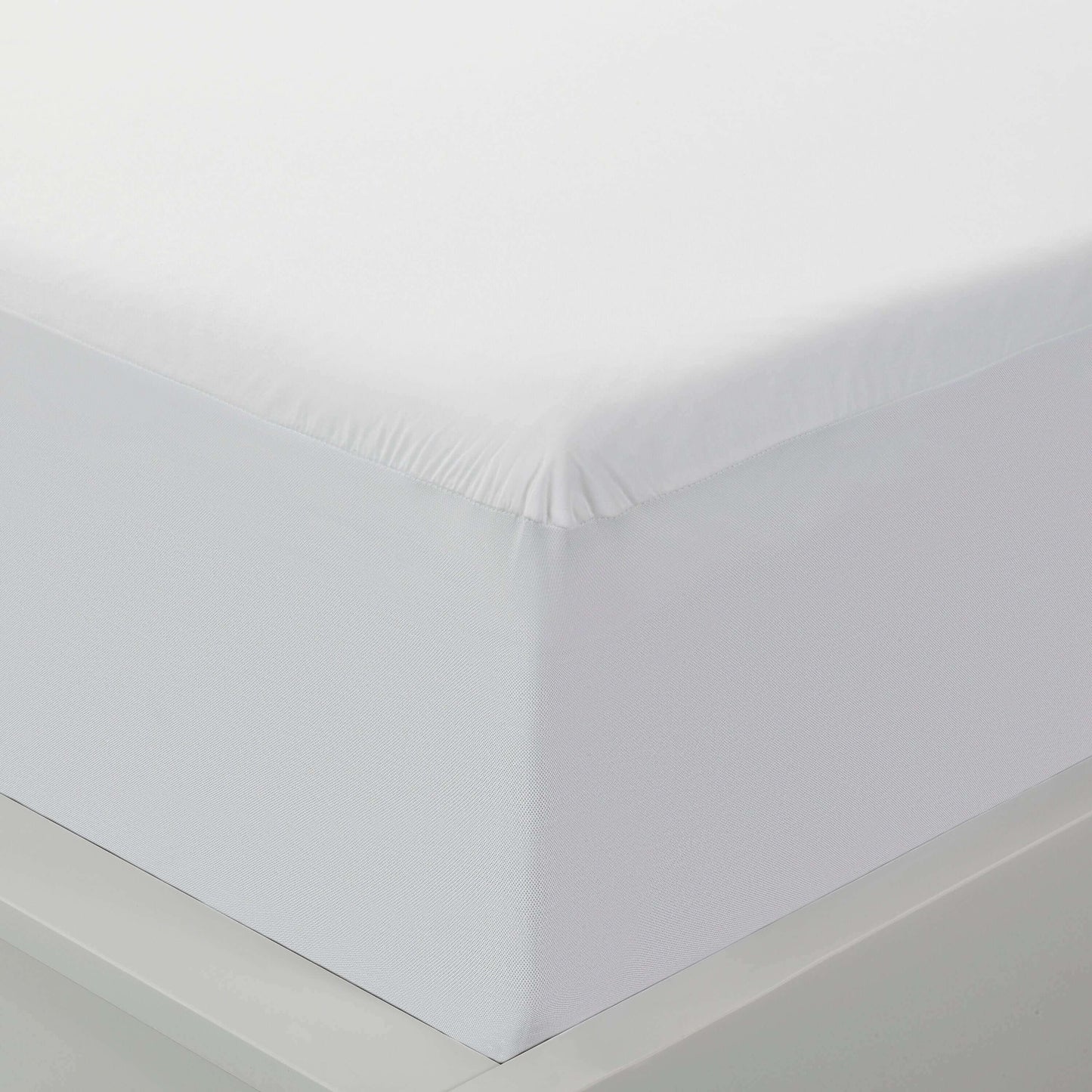 Close-up of a Cool Tencel Waterproof Mattress Protector by PROTECT-A-BED® on a mattress, showcasing its sleek white design.