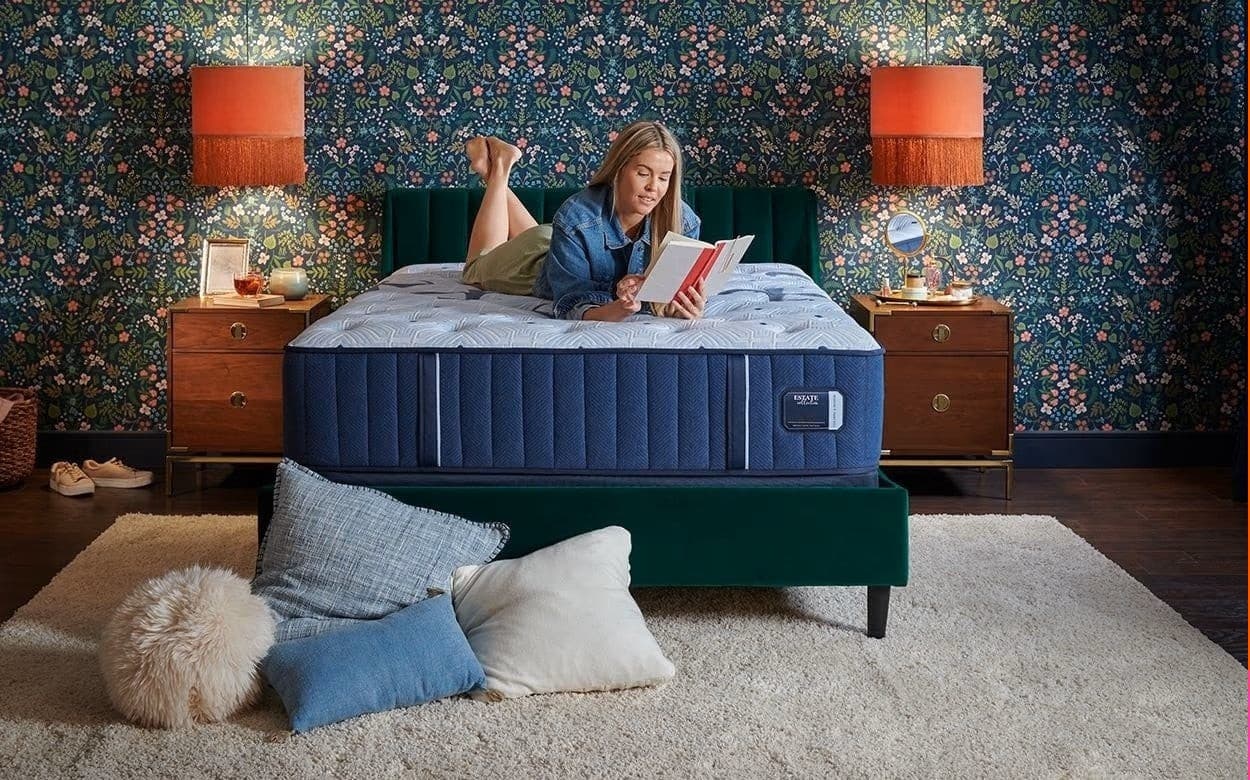 Woman reading a book on the Stearns & Foster Estate 14.5" Plush Mattress in a beautifully decorated bedroom.