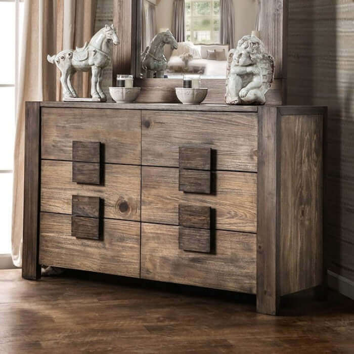 Rustic wooden dresser with block-like pulls, elegant mirror, and decorative statues in a stylish interior setting.