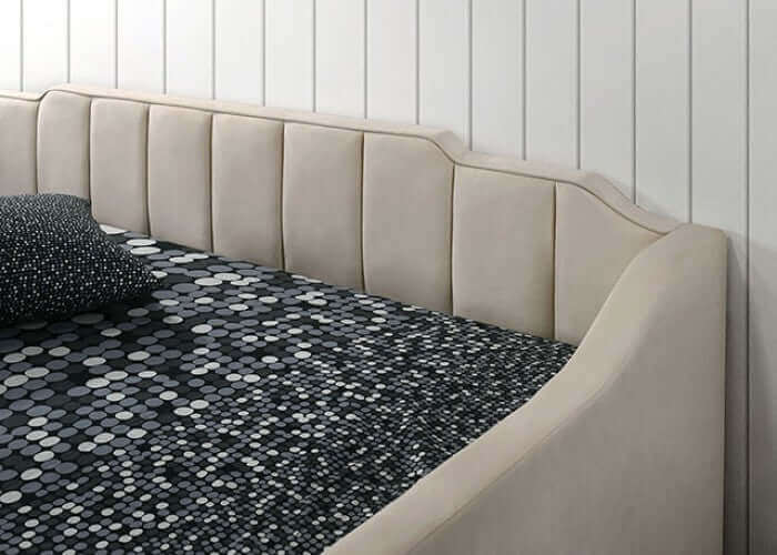 Kosmo Beige Daybed with staircase headboard and sleek vertical channel tufting against a textured patterned bedding.