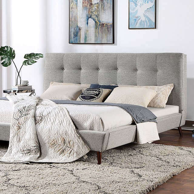 Mid-century modern gray platform bed with padded tufted headboard and stylish bedding in a chic bedroom setting.