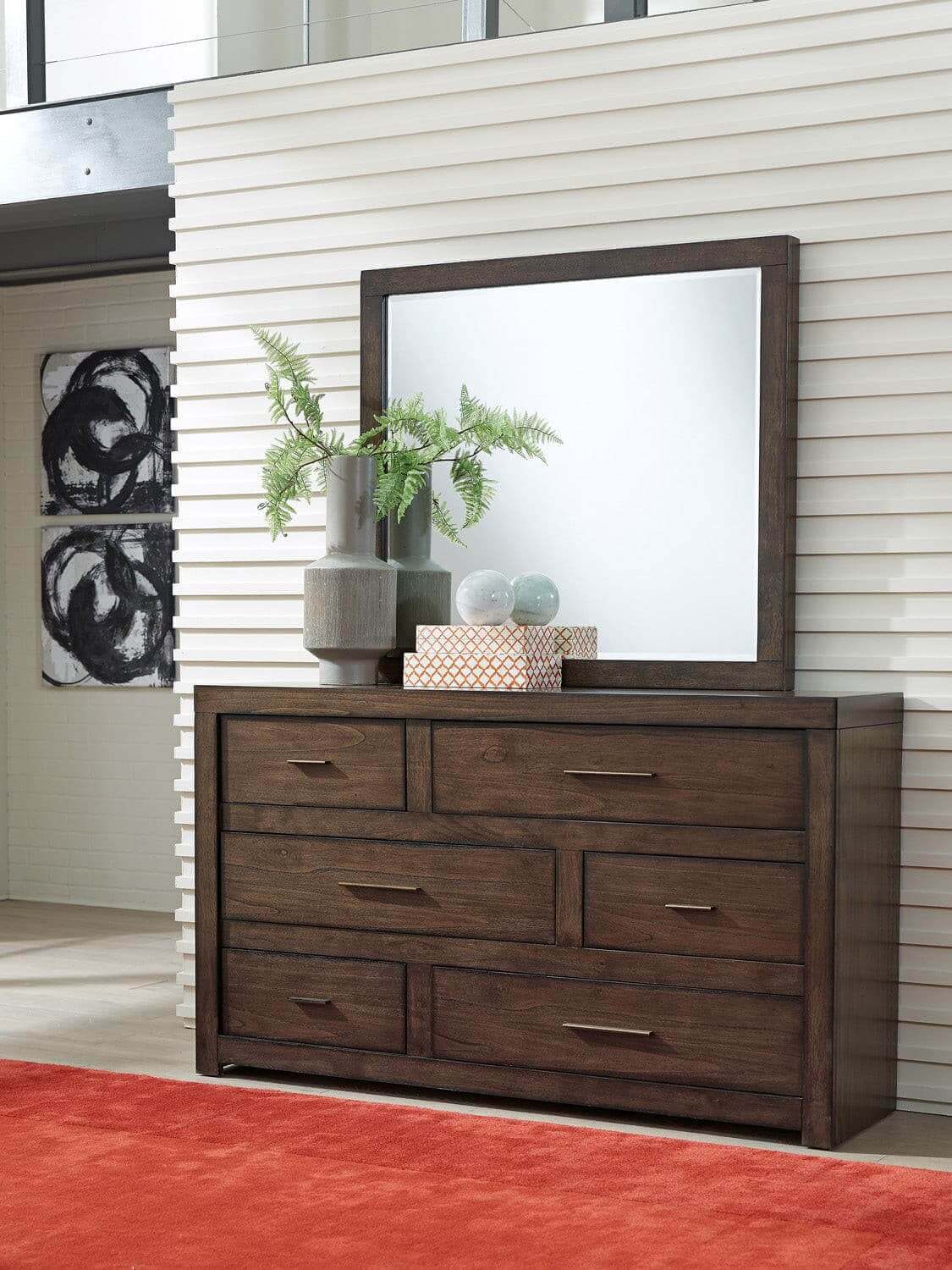 Modern Loft Brownstone dresser with mirror, aged bronze hardware, and decorative plants, enhancing contemporary home decor.