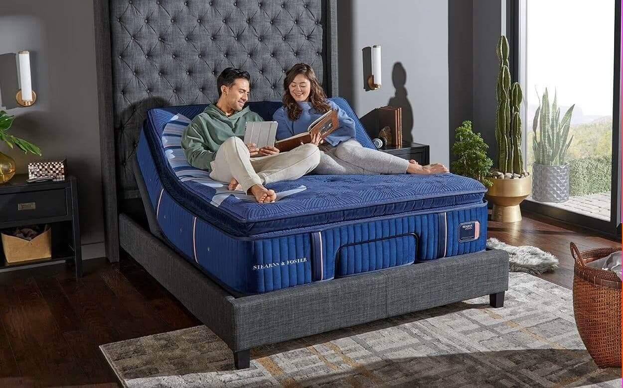 couple enjoying reading on an adjustable bed with a blue mattress in a modern bedroom setting.