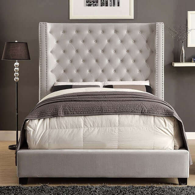 Grey tufted wingback bed with nailhead trim and a cozy bedding setup, perfect for any bedroom style.