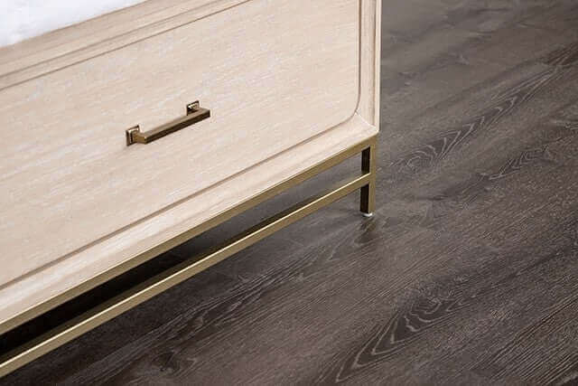 Close-up of Sandnes Light Oak Mid Century Storage Bed Frame's drawer and elegant metal handle on a dark wood floor.
