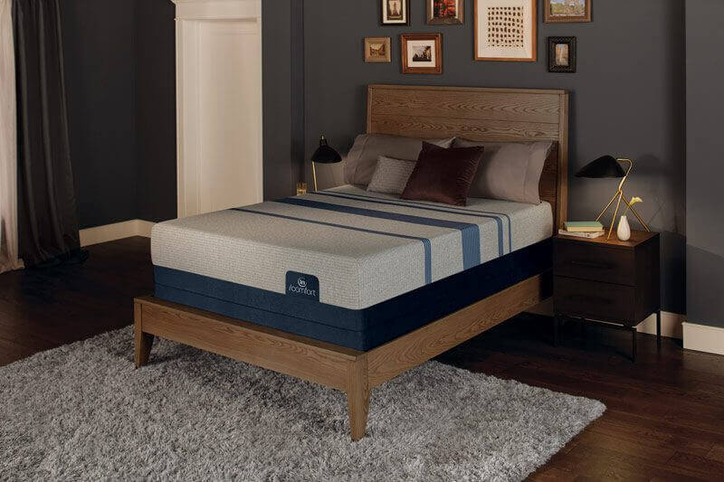 CA King Serta iComfort Blue Max Touch 3000 Plush mattress on a wooden bed frame in a cozy bedroom setting.