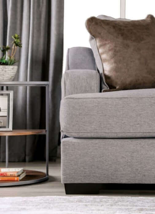 Skyline Gray transitional sofa with plush brown throw pillow and stylish side table in a modern living room setting.