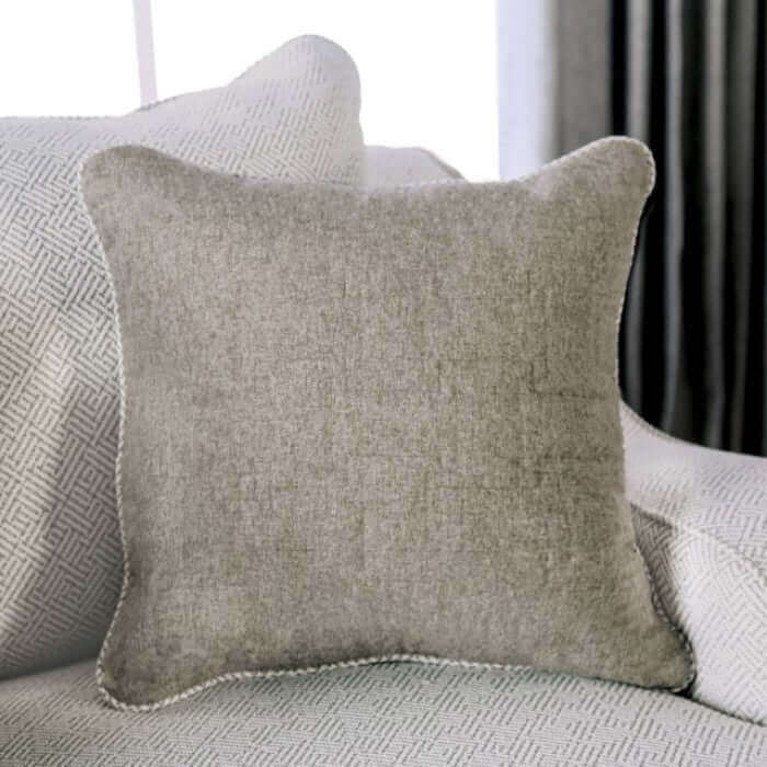 Soft gray throw pillow with welt trim resting on a textured sofa, adding a cozy touch to the living room decor.