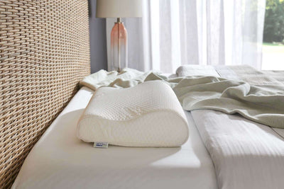 Tempur-Pedic Tempur-Neck Firm Pillow on a bed with soft linen, designed for ergonomic support and comfort.