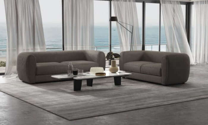 Modern Verdal Gray armchairs in a coastal living room with panoramic windows and a contemporary coffee table.