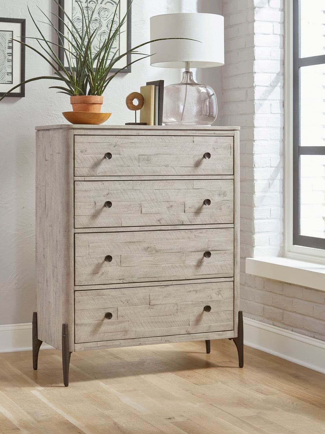 Zane collection chest with four drawers, matte finish, accentuated by black hardware, in a bright, modern room.