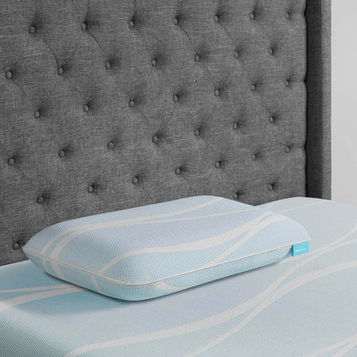 Tempur-Breeze° ProLo Pillow on a bed with tufted gray headboard, showcasing advanced cooling features.