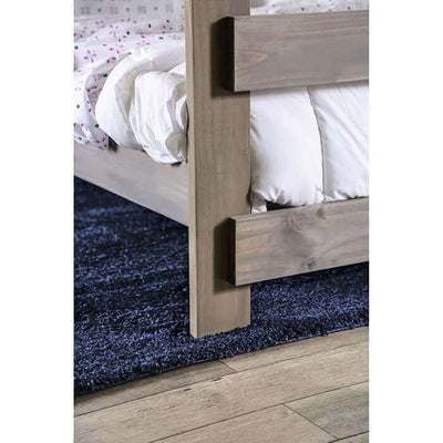 Close-up of Arlette rustic gray pine wood bunk bed corner with cozy bedding and plush blue rug underneath.